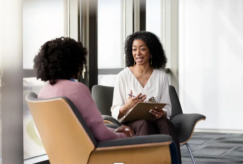 Two colleagues in a supportive one-on-one conversation by an office window